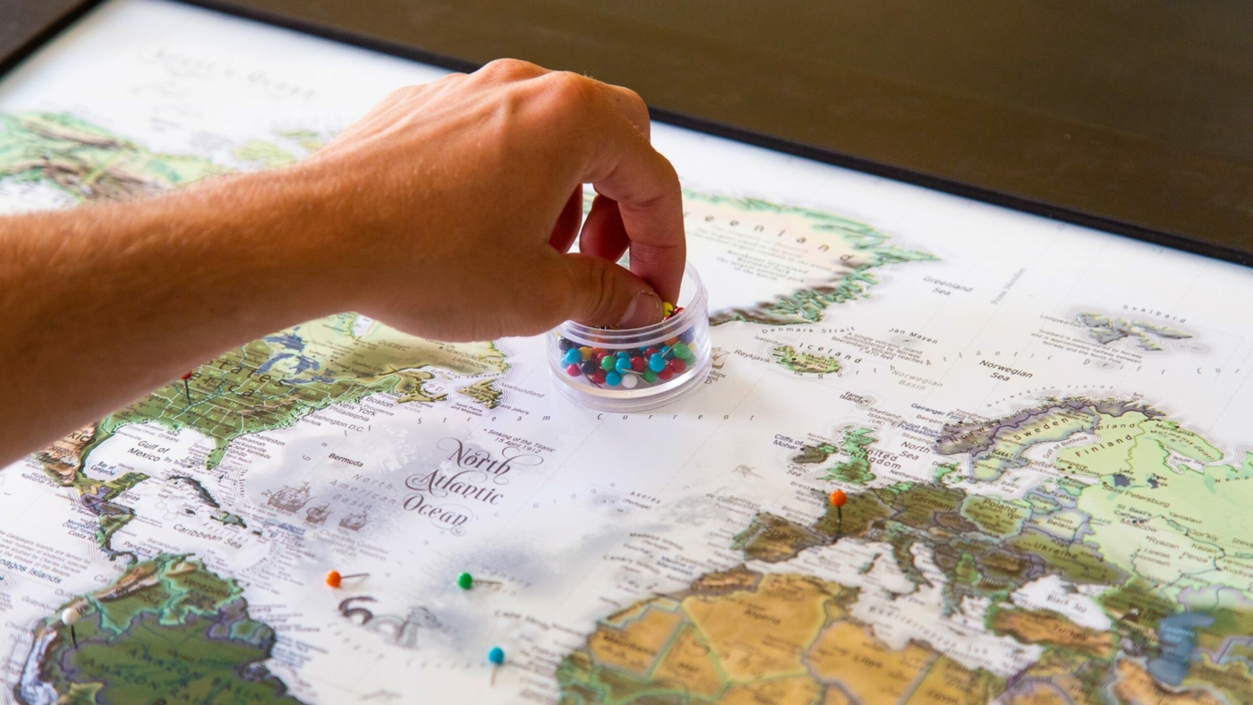 Person placing push pins into World Map.