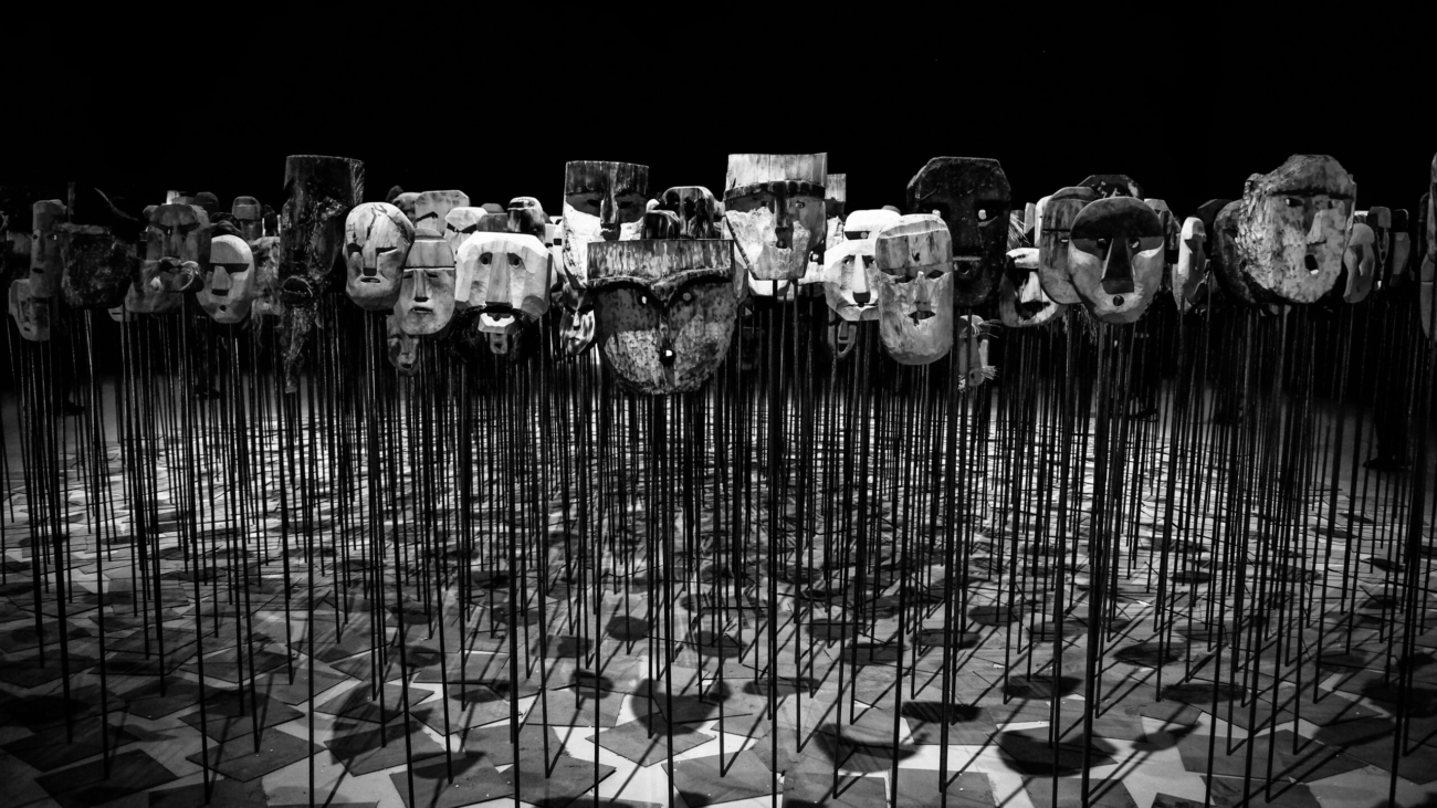 Greyscale photo of masks on a stick