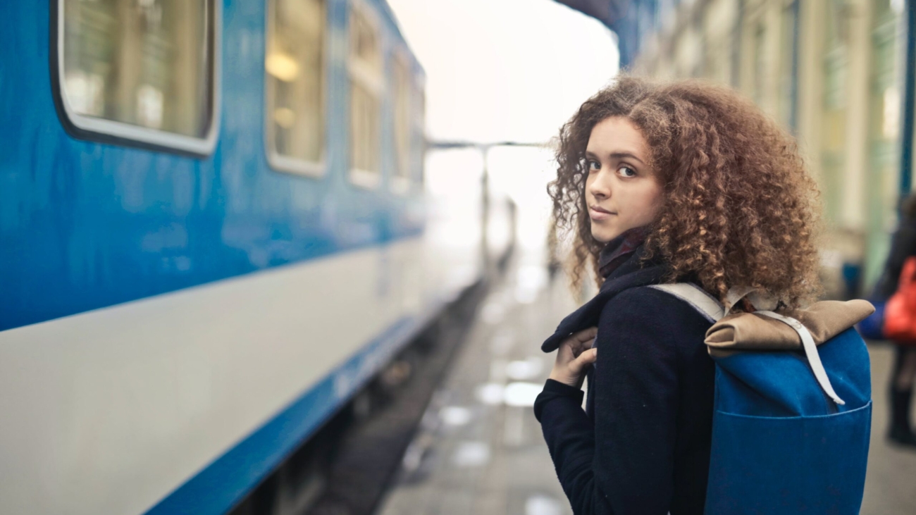 Woman in black coat standing beside blue and white train